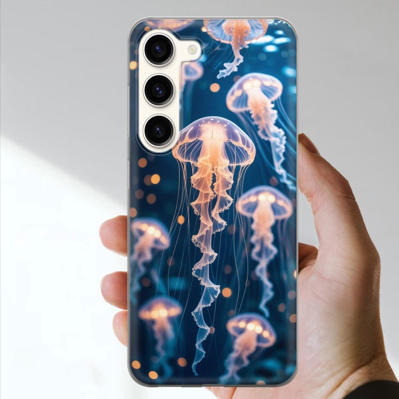 May include: A phone case featuring a vibrant design of glowing jellyfish against a deep blue background. The jellyfish have orange and white details, creating a captivating underwater scene. The case has a clear, protective finish.