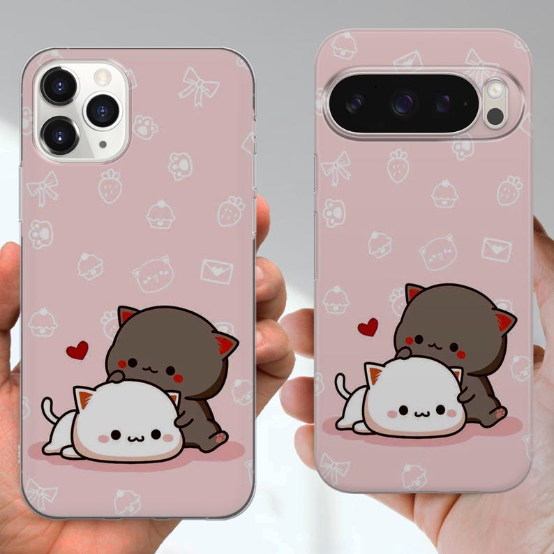 May include: Pink phone cases with a repeating pattern of white bows, strawberries, and cupcakes. Each case features a cartoon illustration of two cats, one brown and one white, with a red heart. The cases are designed for different phone models.