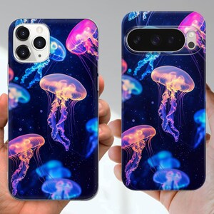 Puede incluir: Fundas de tel&eacute;fono con un dise&ntilde;o vibrante de medusas. Las fundas presentan un fondo azul oscuro con medusas coloridas en tonos rosa, naranja, amarillo y azul. Las medusas tienen largos tent&aacute;culos fluidos.