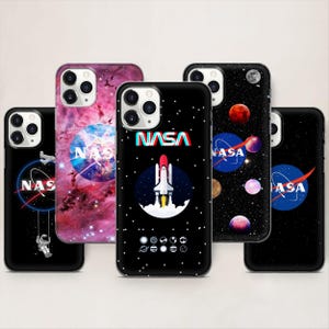 Peut inclure: Plusieurs coques de téléphone avec des motifs spatiaux. Les coques présentent le logo de la NASA, une fusée au décollage, une nébuleuse et des planètes sur fond noir. Certaines coques ont un bord blanc et une découpe pour l'appareil photo.
