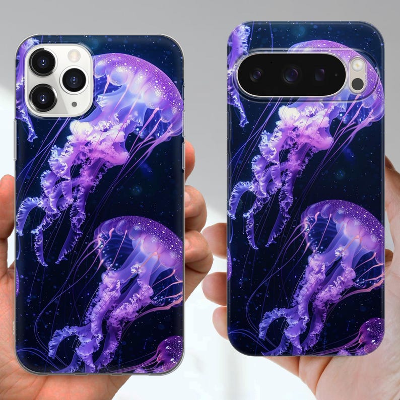 Puede incluir: Dos fundas para tel&eacute;fono con un dise&ntilde;o de medusas. Las fundas tienen un fondo azul oscuro con varias medusas moradas. Las medusas tienen tent&aacute;culos detallados y un brillo suave. Las fundas se sostienen en las manos.