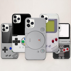 May include: A collection of phone cases with retro video game console designs. The cases feature designs inspired by a PlayStation, a Game Boy, and other classic gaming controllers. The cases are in various colors, including gray, black, and white.