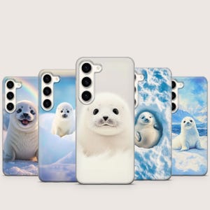 Op de afbeelding: Een verzameling telefoonhoesjes met schattige witte zeehondenbaby's in verschillende arctische scènes. Elke hoes toont een ander ontwerp, waaronder een regenboog, ijsformaties en een besneeuwd landschap. De zeehonden hebben donkere ogen en worden in speelse poses afgebeeld.