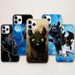 Può includere: Una collezione di custodie per telefoni con immagini del drago Sdentato del franchise "Dragon Trainer". Le custodie mostrano varie scene, tra cui Sdentato con una persona e primi piani del drago.