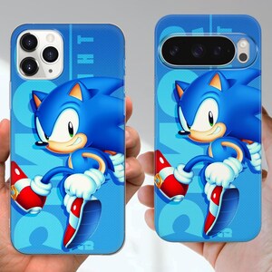 Puede incluir: Fundas de tel&eacute;fono azules con el personaje Sonic the Hedgehog. Las fundas muestran al personaje en una pose din&aacute;mica sobre un fondo azul claro con la palabra "NIGHT" en una fuente estilizada. El dise&ntilde;o incluye los zapatos rojos y blancos caracter&iacute;sticos del personaje.