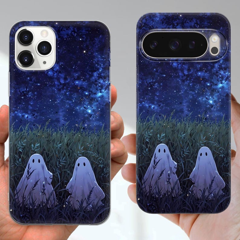 May include: Two phone cases with a night sky design. The cases feature a starry blue background, green grass, and two cartoon ghosts. The cases are designed for different phone models, with camera cutouts.