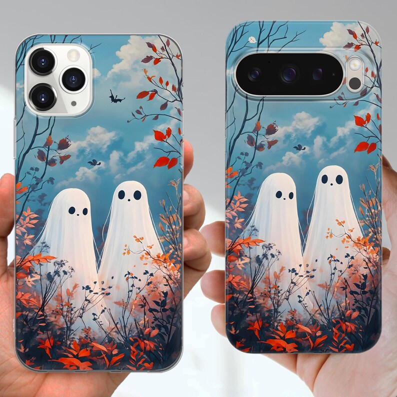 May include: Two phone cases with a whimsical design featuring two white ghost figures against a backdrop of a blue sky with clouds, autumn leaves, and bare tree branches. The cases are for different phone models.