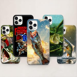 Könnte beinhalten: Eine Auswahl an Handyhüllen mit lebendigen Fischillustrationen. Designs umfassen einen springenden Bass, einen Fisch mit offenem Maul und eine Hülle mit dem Text "Hooked Freed". Die Hüllen sind in verschiedenen Farben wie Schwarz, Blau und Grün.