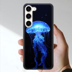 May include: A phone case featuring a vibrant blue jellyfish design against a dark background. The jellyfish has a glowing, ethereal appearance with long, flowing tentacles. The case has a clear border and a camera cutout.