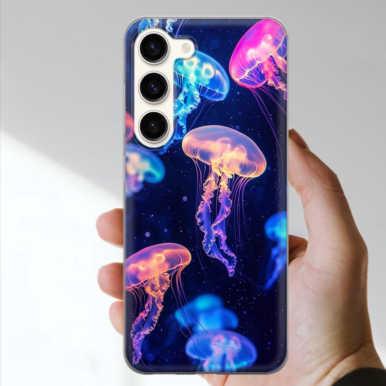 May include: A phone case featuring a vibrant design of glowing jellyfish against a dark blue background. The jellyfish are depicted in shades of pink, orange, and blue, creating a colorful and eye-catching pattern. The case has a glossy finish.
