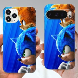 Puede incluir: Dos fundas para tel&eacute;fono con Sonic el Erizo y Tails de la pel&iacute;cula Sonic the Hedgehog. Las fundas tienen un fondo azul con los personajes en primer plano. Las fundas para tel&eacute;fono se sostienen en las manos.