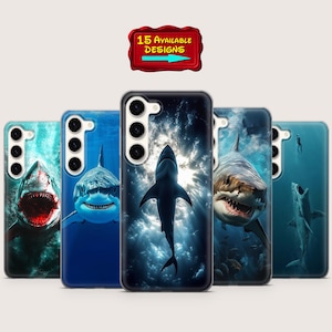 May include: A collection of five phone cases featuring shark designs. The cases display various shark illustrations in shades of blue and white, with one case showcasing a shark against a dark, cloudy background. A red sign indicates "15 AVAILABLE DESIGNS."