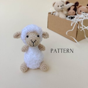 May include: A white crocheted lamb amigurumi toy with black eyes and a brown nose. The toy is sitting on a light beige surface with the word "PATTERN" printed in black below it.
