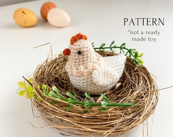 May include: A crocheted chick in a nest made of straw with green sprigs. The chick is white with orange accents. The text "PATTERN *not a ready made toy" is visible in the image.