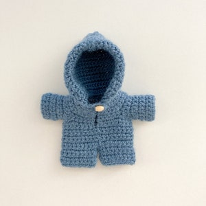 May include: A blue crocheted hooded jacket with a wooden button closure.