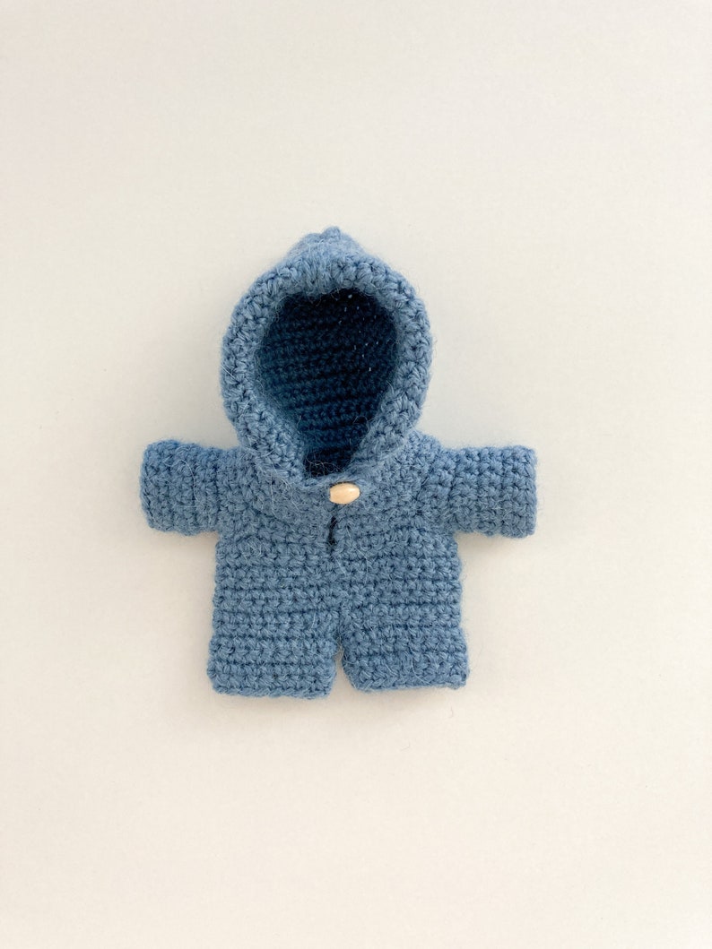 May include: A blue crocheted hooded jacket with a wooden button closure.