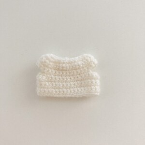 May include: A white crocheted sleeveless top with a rounded neckline.