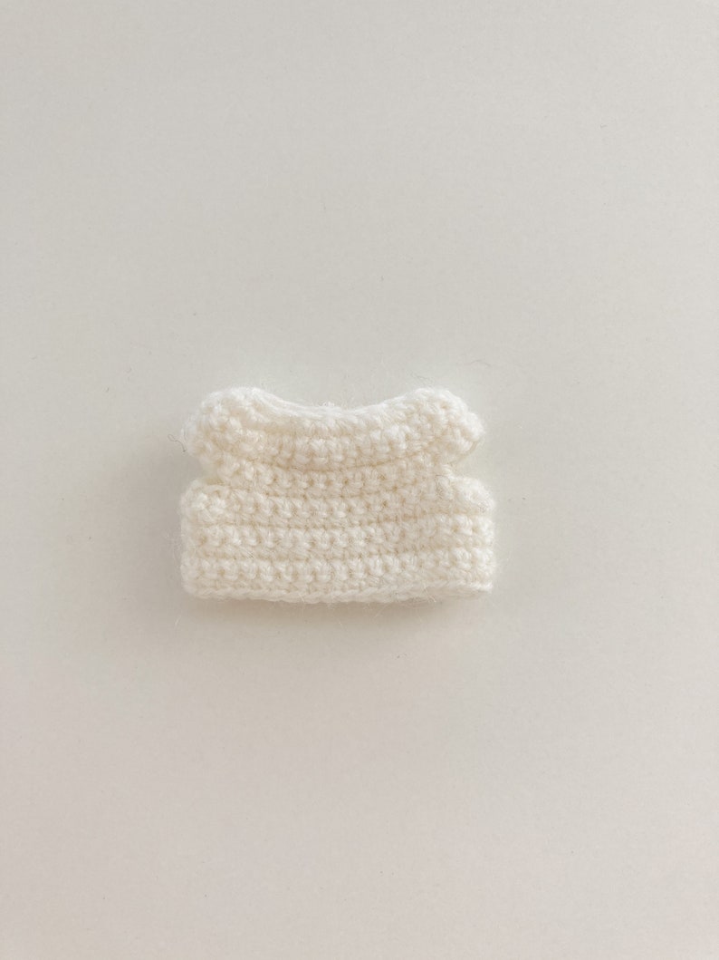 May include: A white crocheted sleeveless top with a rounded neckline.