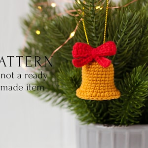 May include: Crochet pattern for a yellow bell ornament with a red bow. The bell is hanging from a green Christmas tree.