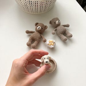 May include: Two brown crocheted teddy bears, a white crocheted dog in a brown crocheted bed, and a small white box with gold accents.