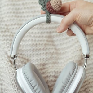 May include: White headphones with gray earcups and a crocheted acorn charm attached to the headband.