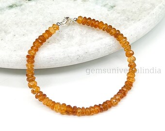 May include: A delicate bracelet made with small, faceted orange gemstones. The bracelet is strung on a silver chain and has a silver clasp.