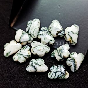 Könnte beinhalten: Eine Sammlung von 12 grünen und weißen Achat-Cabochons in Wolkenform. Die Cabochons sind facettiert und haben ein natürliches, organisches Aussehen.