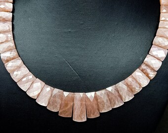 May include: A pink gemstone necklace with faceted beads. The necklace is displayed on a black mannequin bust.