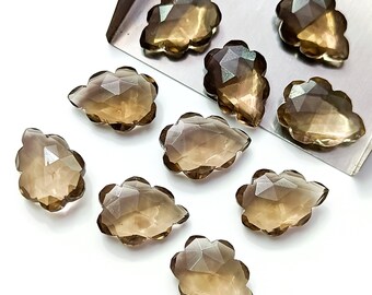 May include: Eight smoky quartz gemstone drops in a cloud shape, with faceted edges. The stones are a light brown color and have a translucent appearance.