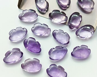 Könnte beinhalten: Eine Sammlung von 15 violetten Amethyst-Cabochons, die in Form einer Blume geschnitzt sind. Die Cabochons sind glatt und poliert und haben einen hellvioletten Farbton.