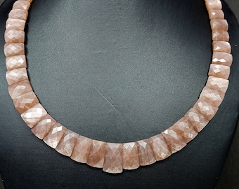 May include: A pink sunstone necklace with faceted beads. The necklace is on a black mannequin bust.