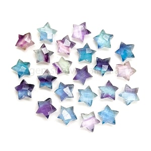May include: A collection of 20 fluorite star-shaped crystal beads in shades of blue, purple, and green. The beads are faceted and have a translucent appearance.