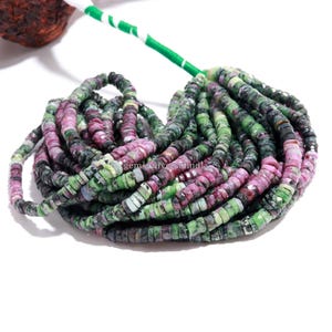 May include: A strand of small, flat, circular disc-shaped beads made of natural stone. The beads feature a mottled pattern of deep forest green, vibrant magenta, and black, with a faceted texture that catches the light along the entire length.