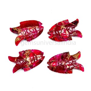 May include: Four red ruby fish carvings with gold accents. The fish are carved in a detailed style and have a glossy finish.