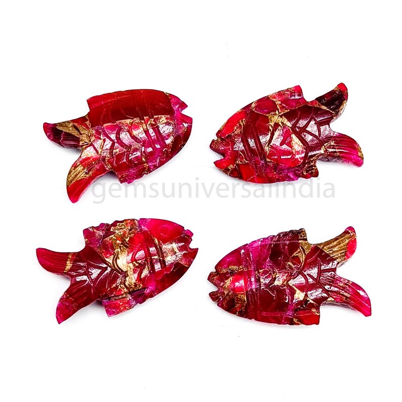 May include: Four red ruby fish carvings with gold accents. The fish are carved in a detailed style and have a glossy finish.