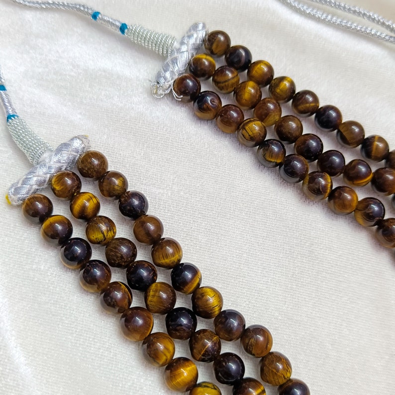 May include: A multi-strand necklace made of brown tiger's eye beads. The necklace has a silver clasp and is strung on a silver cord.