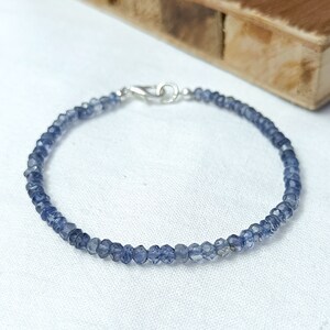 May include: A delicate bracelet made with small, faceted, blue-grey gemstone beads. The bracelet has a silver clasp.
