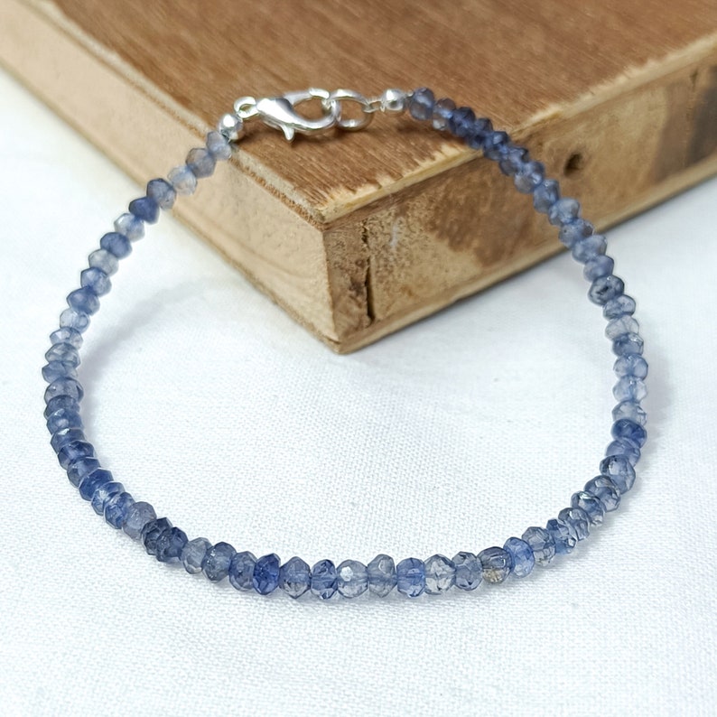 May include: A delicate blue gemstone bracelet with a silver clasp. The bracelet is made of small, faceted beads and is perfect for everyday wear.