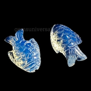 May include: Two blue and white opal fish carvings. The fish are detailed with scales and fins.