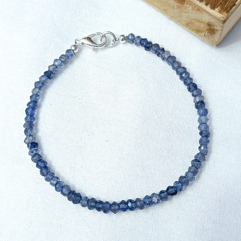 May include: A delicate blue gemstone bracelet with a silver clasp. The bracelet is made of small, faceted beads and is perfect for everyday wear.