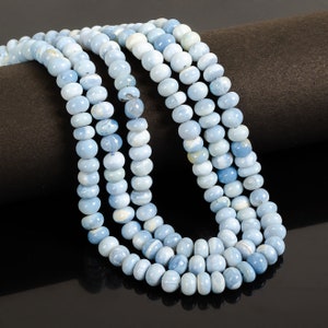 May include: A strand of light blue opal beads. The beads are round and smooth, and they have a slightly iridescent sheen.