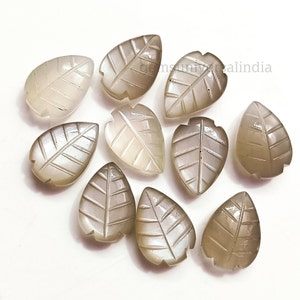May include: Ten gray moonstone leaf shaped beads with a carved leaf design. The beads are approximately 1 inch long.