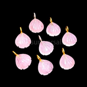 May include: Eight pink rose quartz flower charms with gold-tone accents. The charms are shaped like flower petals and have a delicate, feminine look.