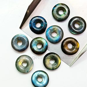May include: Ten iridescent labradorite donut beads with a hole in the centre. The beads are various shades of blue, green, and brown.