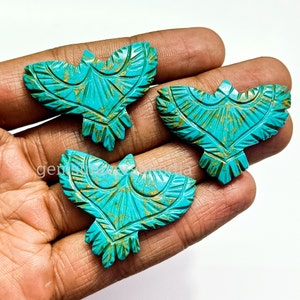 May include: Three turquoise blue carved bird pendants with gold accents. The birds are facing forward with their wings spread out.