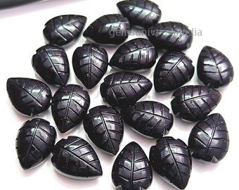 May include: A collection of 20 black gemstone leaf-shaped cabochons. The cabochons are carved with a detailed leaf pattern and have a glossy finish.