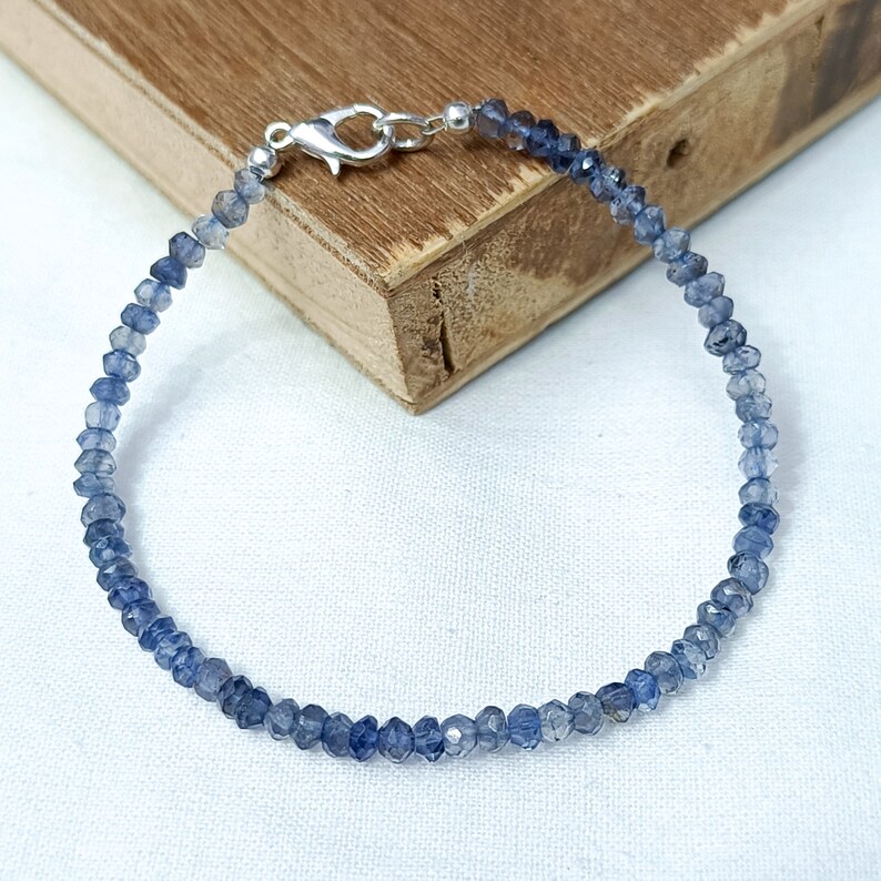 May include: A delicate blue gemstone bracelet with a silver clasp. The bracelet is made of small, faceted beads and is perfect for everyday wear.
