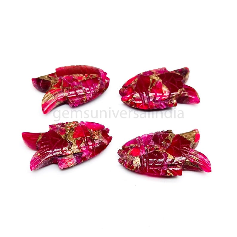 May include: Four pink and gold fish shaped gemstone pendants. The pendants are carved from a pink and gold stone with a marbled pattern.
