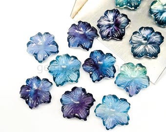 May include: Assortment of blue and purple flower-shaped cabochons. The cabochons are made of a translucent material with a slight iridescent sheen.