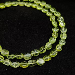 May include: A strand of light green oval-shaped beads. The beads are translucent and have a slightly frosted appearance.